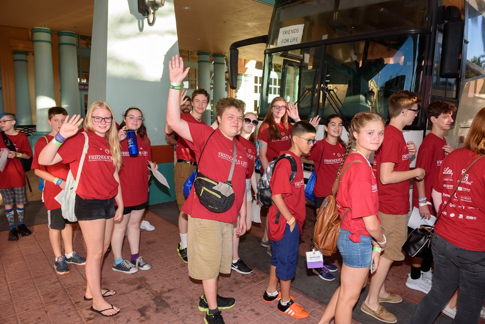 Teens wave as they board busses for Animal Kingdom